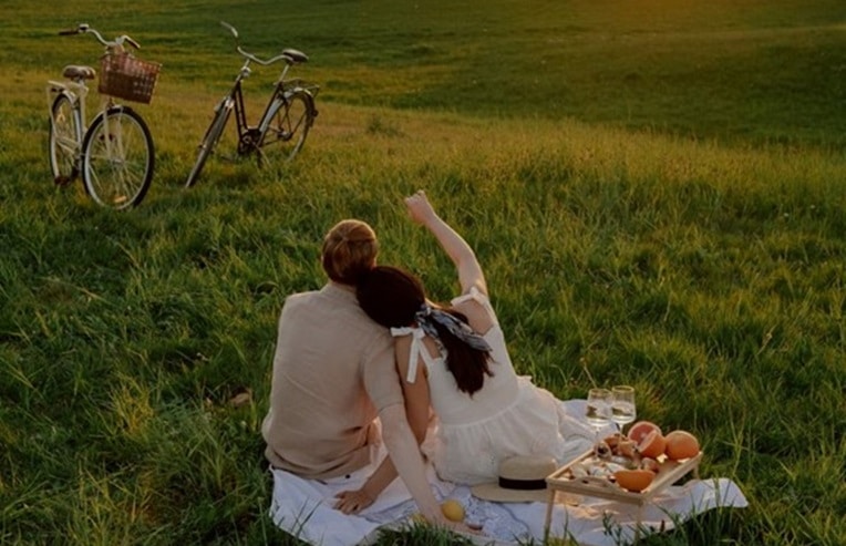 People sitting on a blanket in a field with bicycles and a basket of fruit for circadian rhythm fasting