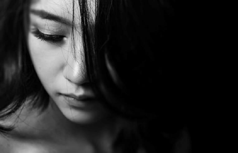 estrogen and depression, black and white photo of woman looking down without smile