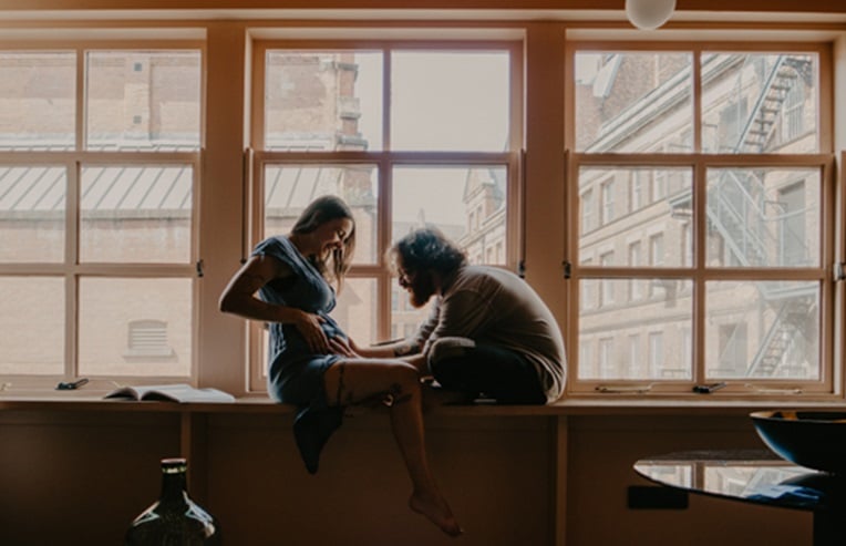 a pregnant woman and male person sitting on a window sill, preconception guide to pregnancy