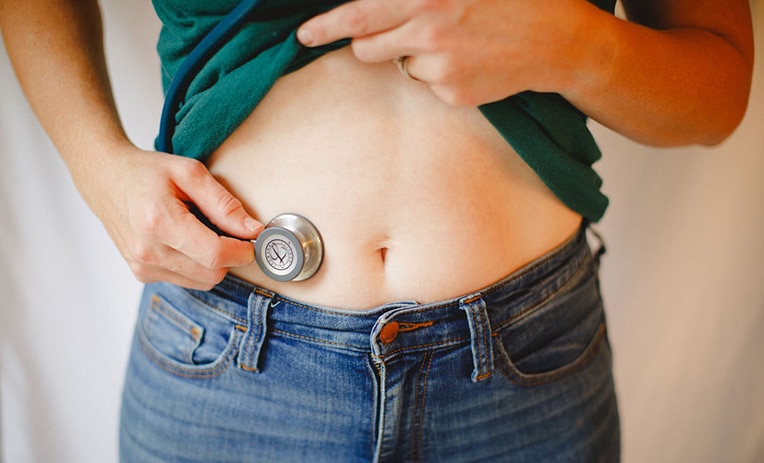 a stethascope on a female abdomen for gut health for hormonal balance