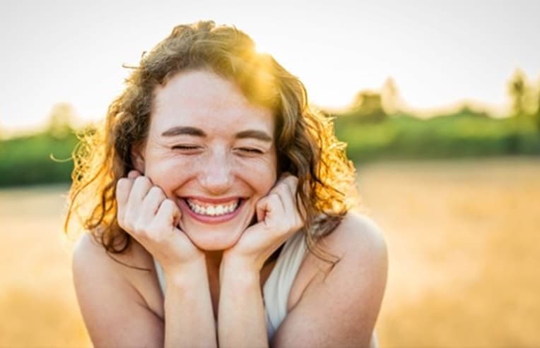 A women smiling in an open field for herbs for perimenopause