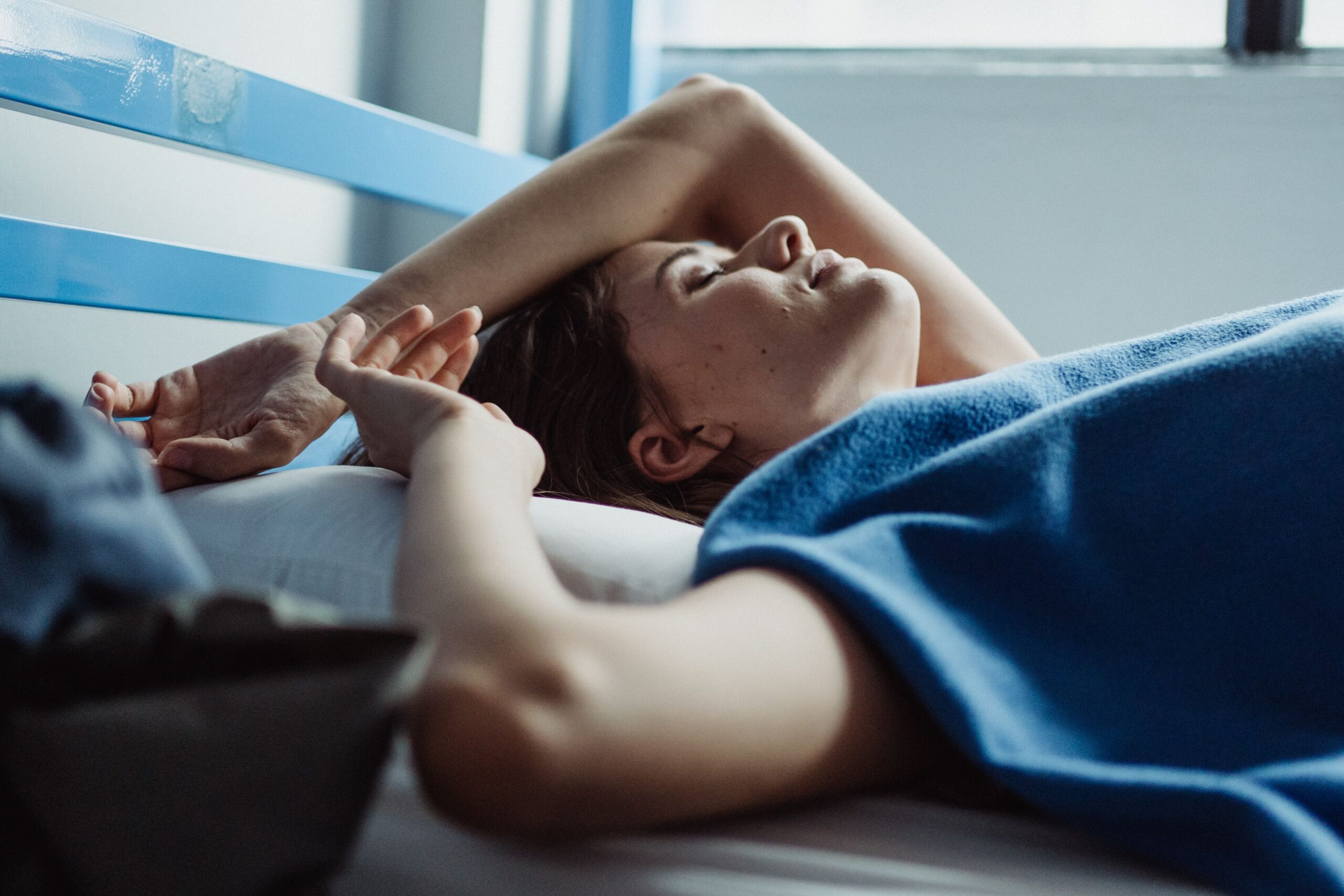 a woman lying down on a bed in sunlight