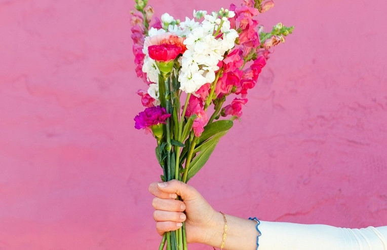 A female's hand holding a bouquet of flowers for foods and herbs for hormonal balance